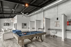 a pool table sits in the middle of a room with a brick wall  at Parkwest Apartment Homes, Hattiesburg