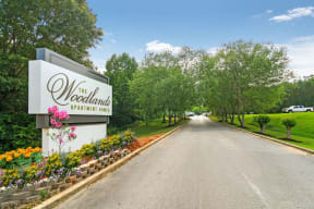 a street with a sign that says the woodlands with trees and flowers in front of it
