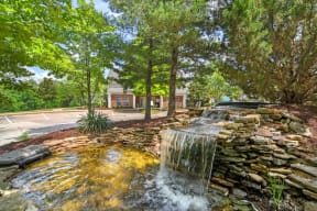a waterfall in a park with a building in the background