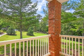 a brick column on a balcony with trees in the background