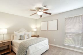 a bedroom with a large window and a ceiling fan
