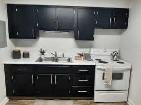 a kitchen with black cabinets and white appliances