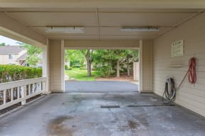 an empty garage with a driveway and trees in the background