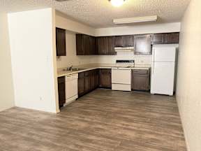 A kitchen with white appliances and brown cabinets.