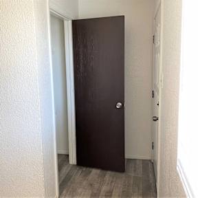 A brown door is in a white hallway.