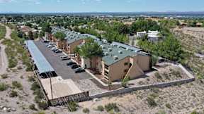 A building with a green roof is surrounded by a parking lot.
