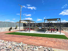 A picnic area with a table and chairs is set up in a park.