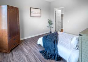 A bedroom with a bed, a dresser, and a painting on the wall.