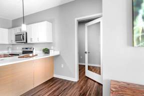 A kitchen with white cabinets and a wooden floor.