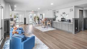 A spacious living room with a blue sofa and a kitchen area in the background.