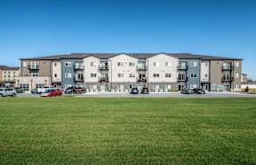 A large apartment complex with a parking lot in front.