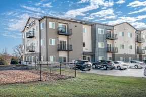 Apartment complex with cars parked in front.