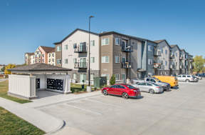 A row of modern apartment buildings with cars parked in front.