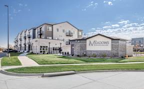The Meadows apartment complex is a modern building with a spacious front lawn.