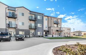 A modern apartment complex with a parking lot in front.