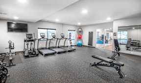 A spacious gym with treadmills, exercise bikes, and other equipment.