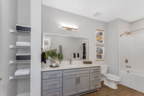 a bathroom with gray cabinets and white walls