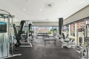 a spacious fitness center with exercise equipment and a large window with a view of the city