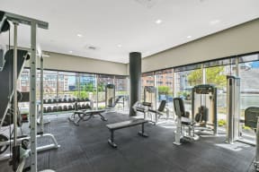 a fitness center with cardio equipment and windows with a view of the city