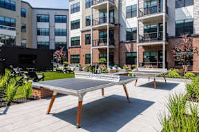 A table tennis table is in the middle of a courtyard.