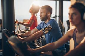 Three people are working out on exercise bikes in a gym.