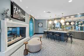 A modern living room with a fireplace and a kitchen area.