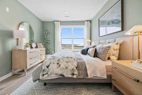 A bedroom with a large bed, a dresser, and a window with a view.