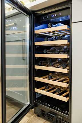 A wine cooler with several shelves of wine bottles.