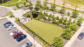 A parking lot with cars and a green field.