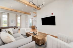 a living room with white furniture and a tv on the wall
