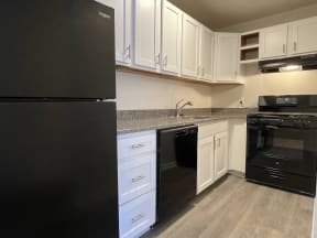 a kitchen with white cabinets and black appliances at Barracks West in Charlottesville, VA