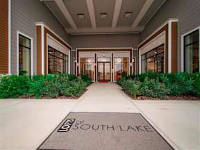 Grand entryway to Lofts at South Lake apartments with beautiful landscaping leading to covered entrance with large doors at Lofts at South Lake, Florida, 34711