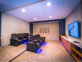 A private movie theater room with tiered comfortable leather chairs and large screen at Lofts at South Lake at Lofts at South Lake, Clermont, FL, 34711