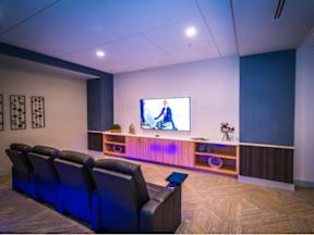 A resident movie theater room with reclinable seating and a large TV screen at Lofts at South Lake apartments at Lofts at South Lake, Clermont, FL, 34711