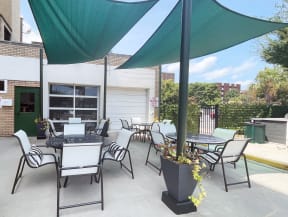a patio with chairs and tables and a grill