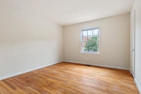 Spacious bedroom with window and hardwood flooring at Barracks West apartments in Charlottesville, VA