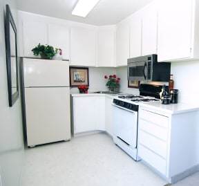 A kitchen with white cabinets and a white stove a stainless steel over the range microwave and an almond fridge a few accents in the kitchen of a unit Prodesse Property Group 1211 Garbo Way  San Jose,