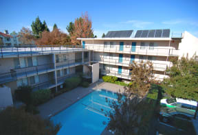 A high sky view of the Aegena apts inner courtyard with a pool the beige building wraps around the pools with trees in the background Prodesse Property Group 1211 Garbo Way  San Jose, CA 95117