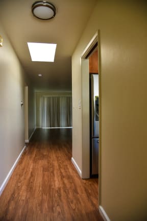 a long hallway with wood floors and a ceiling with a skylight