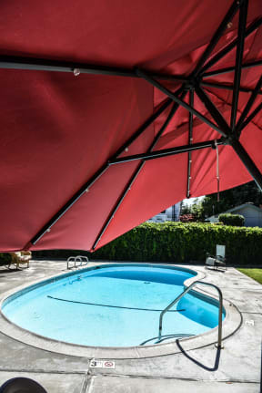 a large red patio umbrella over a pool