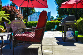 a patio with chairs and umbrellas and a grill