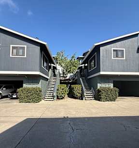 Two houses with grey exteriors and staircases leading to the second floor.