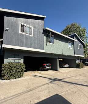 A grey house with a garage and a car parked in it.