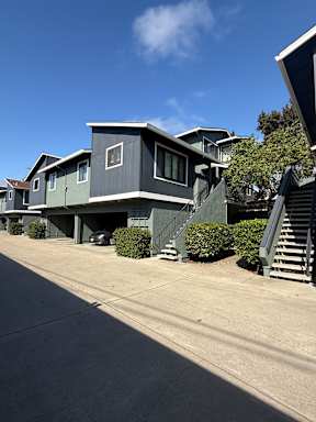 A grey house with a car parked in front.