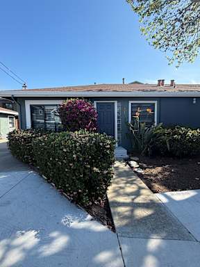 A house with a grey roof and a grey front door with a small garden in front.