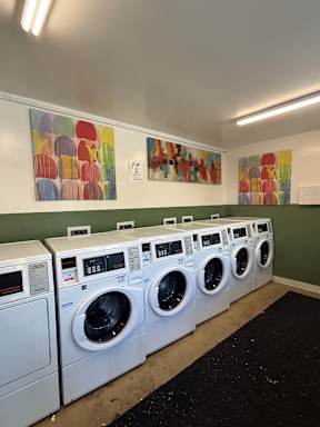 A row of white front load washing machines in a laundromat.