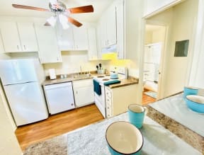 a kitchen with white appliances and a ceiling fan