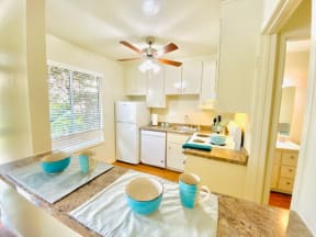 a kitchen with a table and a ceiling fan