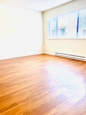 an empty room with wood floors and a window