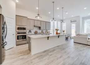 A modern kitchen with a refrigerator on the left and a dining area with a white sofa.